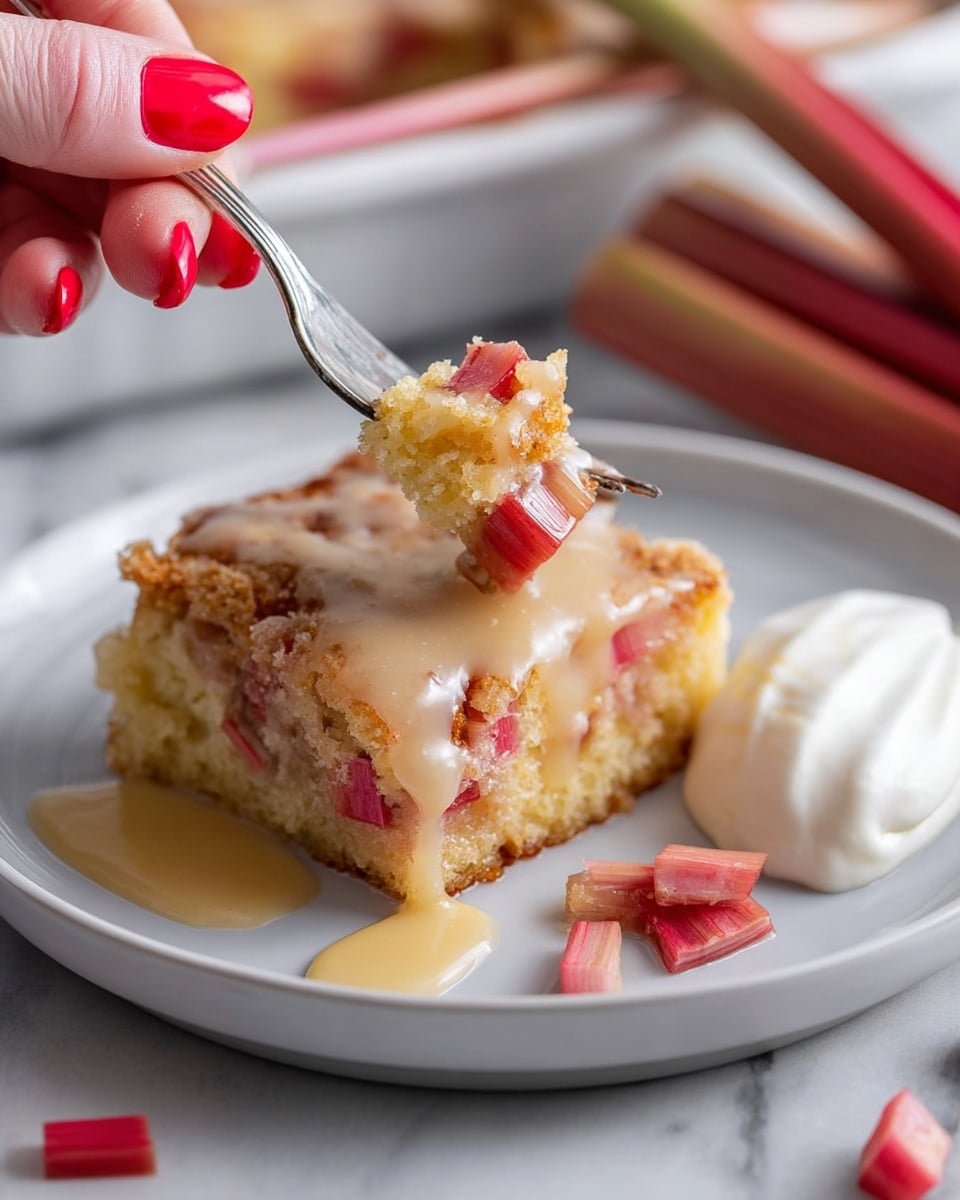 A piece of rhubarb cake sits on a white plate with a soft, thick bottom layer of light yellow cake embedded with visible chunks of red and pink rhubarb. The top layer is a golden, crumbly crust covered with a shiny, creamy sauce that drips slightly onto the plate. To the right side of the cake on the plate is a dollop of white whipped cream. A woman's hand with bright red nail polish holds a fork piercing a piece of the cake, lifting it slightly off the plate. Small pieces of rhubarb are scattered on the white marbled surface around the plate, and blurred stalks of rhubarb appear in the background. Photo taken with an iphone --ar 4:5 --v 7