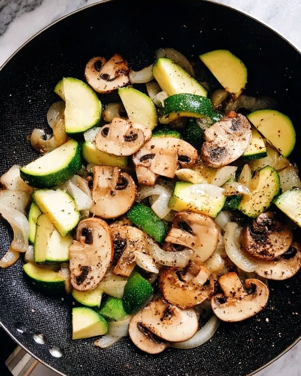 The image shows a black pan filled with cooked vegetables including light brown mushroom slices, white onion strips, and bright green zucchini wedges. The vegetables look soft and slightly browned, with some black pepper sprinkled on top. The pan sits on a white marbled surface. photo taken with an iphone --ar 4:5 --v 7
