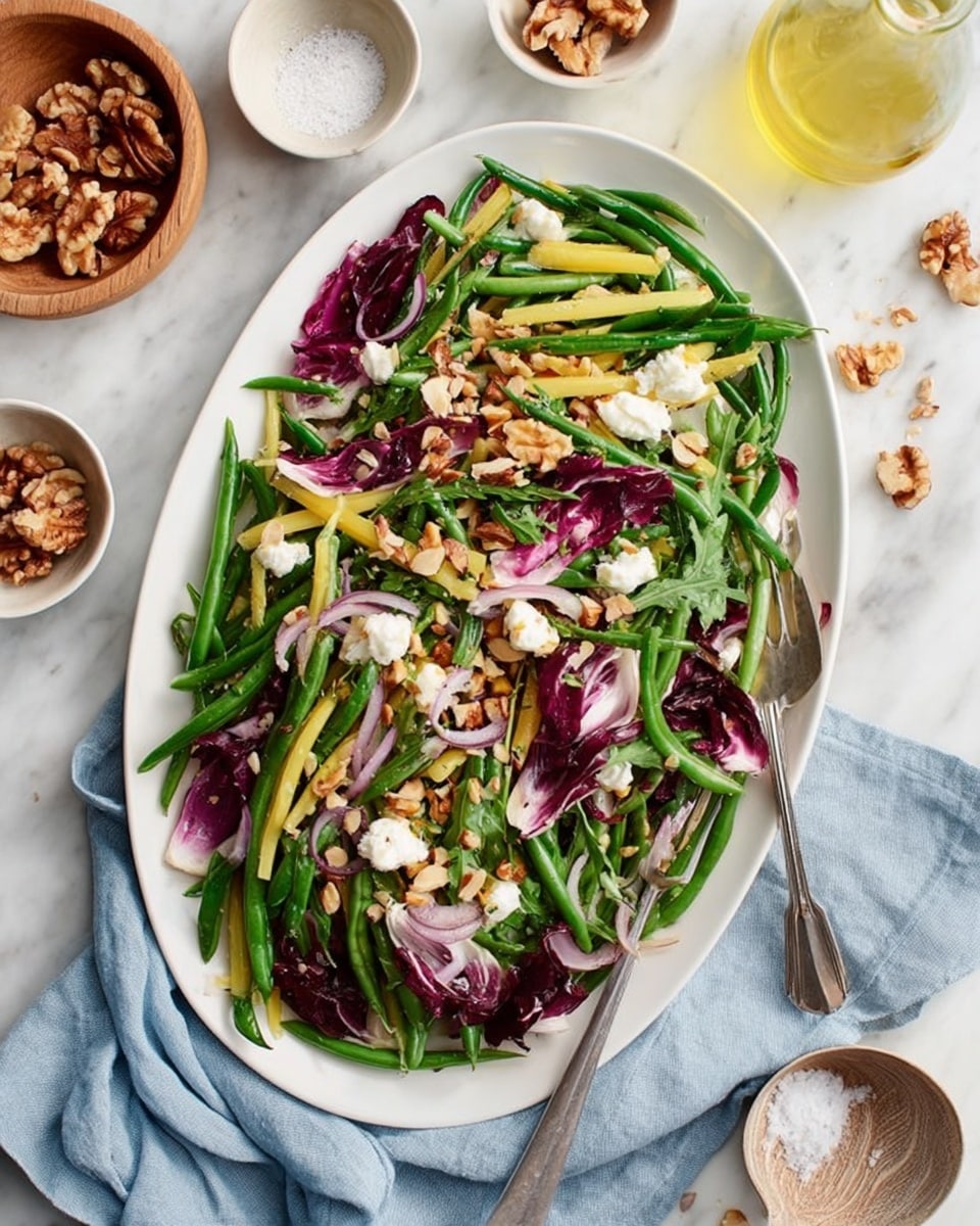 The image shows a white oval plate filled with a fresh salad made of bright green and yellow beans as the base layer, mixed with deep purple radicchio leaves and thinly sliced light red onions. On top, there are scattered small white dollops of cheese and a generous sprinkle of chopped walnuts and almond slices, adding texture and color contrast. The plate is set on a white marbled surface with a light blue cloth napkin nearby, and a silver fork and spoon rest on the right side of the plate. Surrounding the plate are small white bowls containing more walnut pieces and almond slices, a small wooden bowl with coarse salt, and a glass bottle of light yellow dressing. photo taken with an iphone --ar 4:5 --v 7