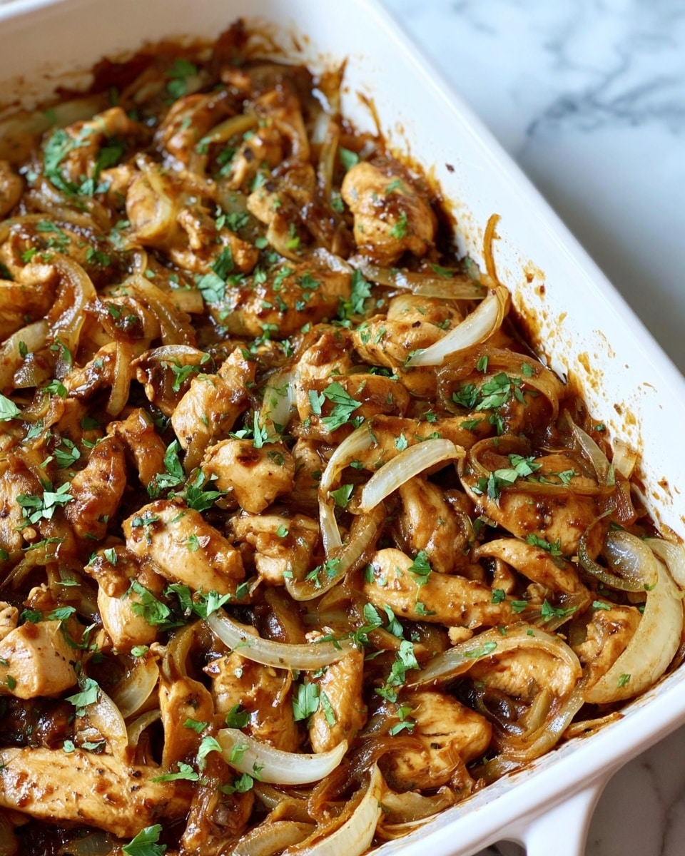 The image shows a white rectangular baking dish filled with a cooked dish made mainly of sliced light brown chicken pieces and thinly sliced translucent white onions. Both the chicken and onions are coated evenly with a rich, glossy brown sauce. The dish is sprinkled with fresh green herbs, adding a touch of color contrast against the brown and white ingredients. The inside edges of the dish have some sauce stains, showing the dish was baked or cooked in it. The dish is placed on a white marbled surface. photo taken with an iphone --ar 4:5 --v 7