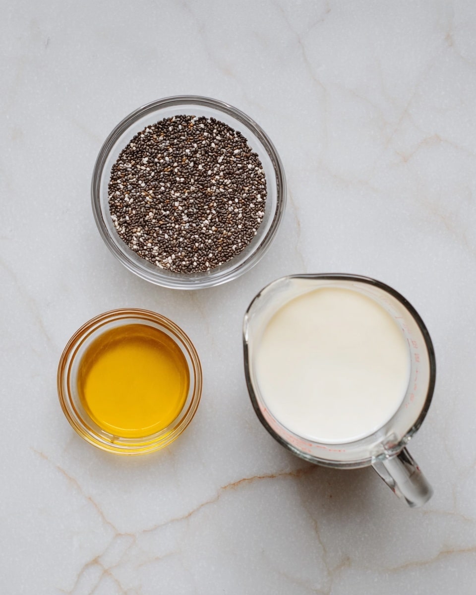 The image shows three clear glass containers placed on a white marbled surface. On the top left, there is a small bowl filled with dark brown and white chia seeds, showing their tiny, round texture. Below to the left, a smaller bowl holds a golden liquid, likely honey, with a smooth and shiny surface. On the right side, a larger measuring cup contains a white liquid, possibly milk or a milk substitute, filling about half of the container. The setup is simple and clean, highlighting the textures and colors of each ingredient. photo taken with an iphone --ar 4:5 --v 7