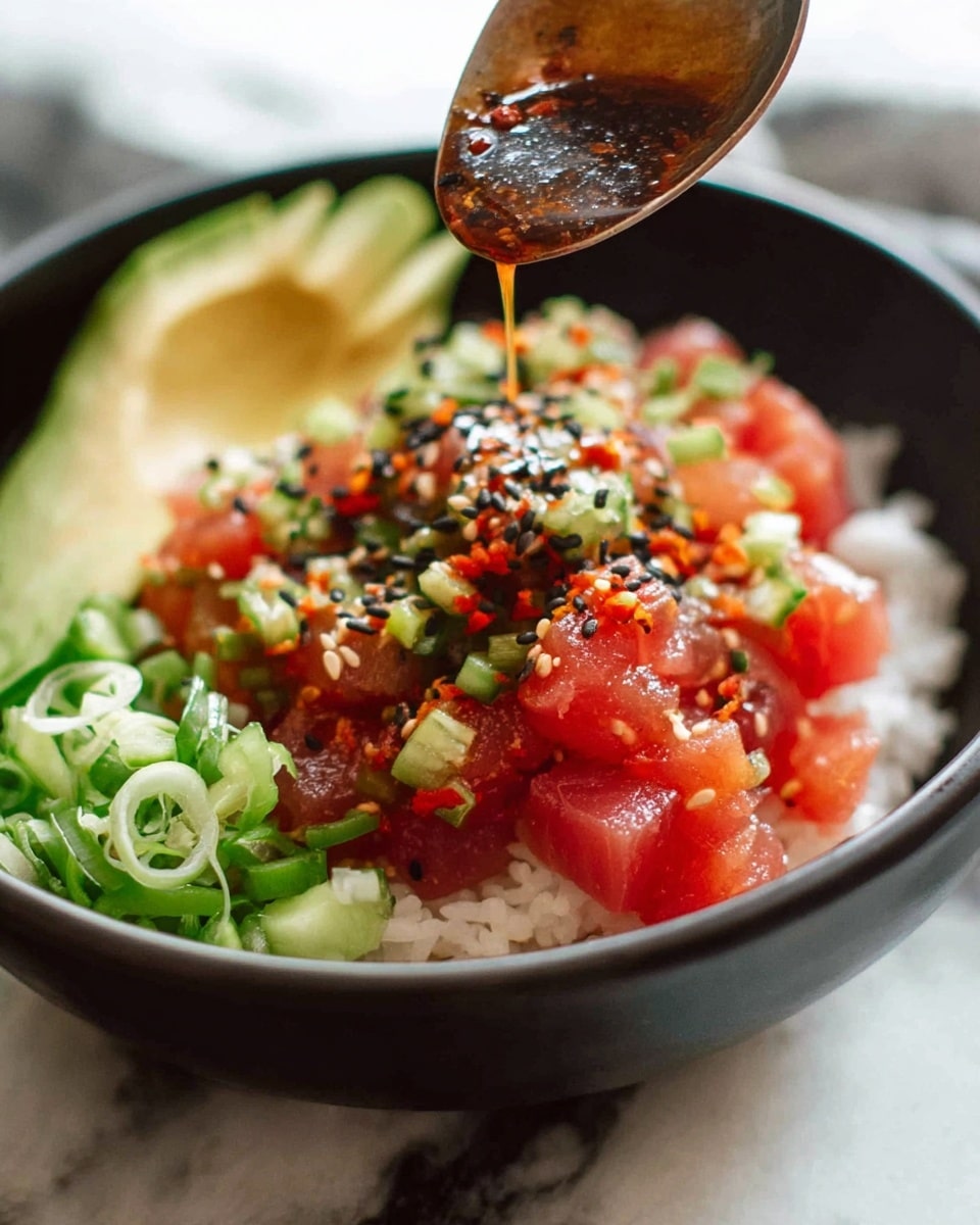 A close-up of a black bowl filled with a layered poke dish on a white marbled surface. The bottom layer is white rice, topped with small cubes of bright red raw fish mixed with chopped green cucumber and bits of red chili, sprinkled with black sesame seeds. On one side of the bowl, there are thin green onion slices and a wedge of pale green avocado. Above the bowl, a spoon held by a woman's hand is dripping a dark brown sauce over the fish mixture. The colors are fresh and vibrant with a mix of red, green, white, and black. photo taken with an iphone --ar 4:5 --v 7