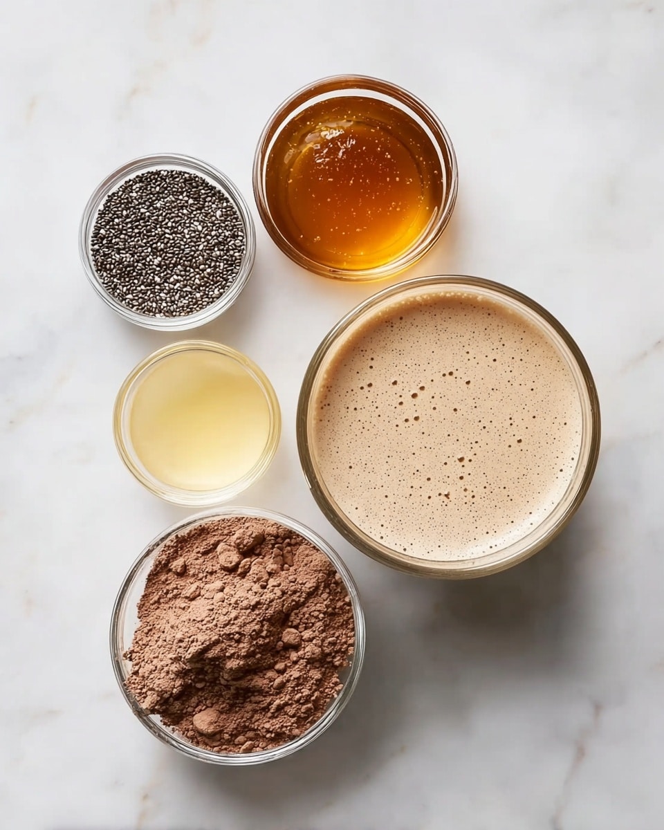 Five glass bowls with different ingredients sit on a white marbled surface. The largest bowl, at the bottom right, holds a light brown creamy liquid with small bubbles on the surface. To its left, a medium bowl contains small black and white chia seeds. Above the chia seeds bowl, a smaller one is filled with dark amber honey, shiny and smooth. Above the honey, another small bowl holds a pale yellow clear liquid. To the left of the pale yellow liquid, a medium bowl is filled with loose, powdery light brown cocoa powder with some small clumps. The bowls are neatly arranged, showing a mix of smooth, powdery, and granular textures. Photo taken with an iphone --ar 4:5 --v 7