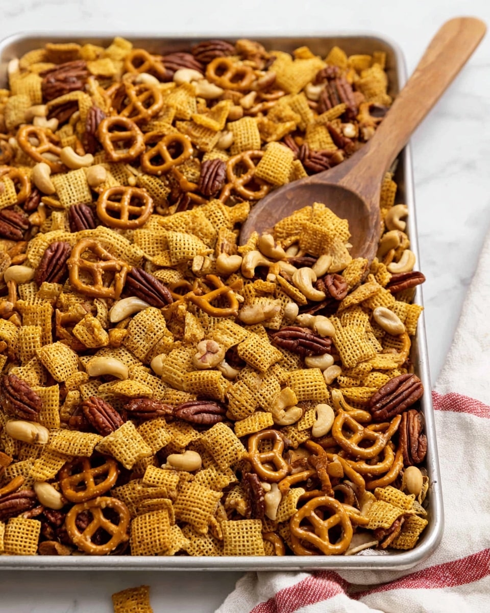 A large silver tray filled with a mix of crunchy snacks including small pretzels, square yellow and light brown cereal pieces with a waffle texture, and various nuts like cashews and pecans spread evenly across the tray. A wooden spoon with a smooth texture and a slightly dark wood grain lies on the right side, partially resting on the snacks. The tray is placed on a white marbled surface, and a white cloth with red stripes is barely visible at the bottom edge of the image photo taken with an iphone --ar 4:5 --v 7