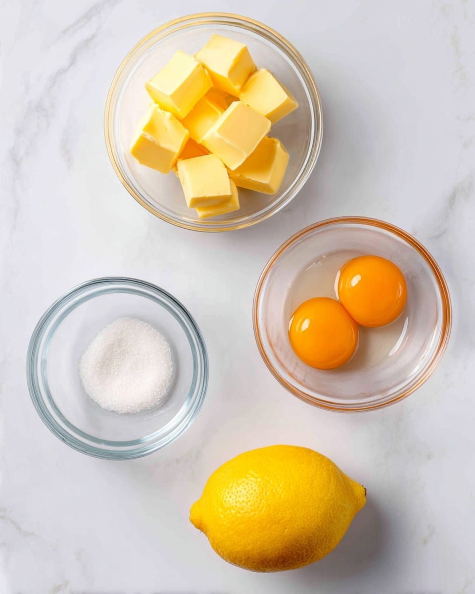 The image shows four baking ingredients placed on a white marbled surface. At the top left is a small clear glass bowl filled with yellow butter cubes, and to the right of it is a similar bowl containing three bright orange egg yolks. Below the butter bowl is a small clear empty bowl labeled sugar, and in the center at the bottom is a whole bright yellow lemon with a slightly textured skin. Photo taken with an iphone --ar 4:5 --v 7