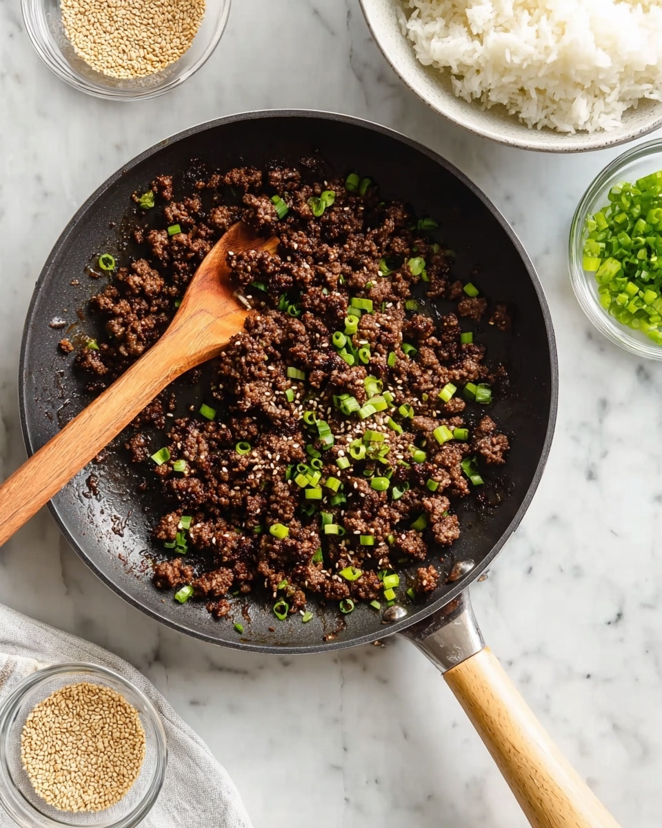 A black skillet filled with cooked ground meat that is dark brown and slightly crispy, sprinkled with bright green chopped scallions scattered evenly on top. A wooden spoon with a natural light brown color rests inside the skillet, partially stirring the meat. To the side, there's a small clear bowl of sesame seeds and another clear bowl filled with more fresh chopped scallions. Above the skillet, a white bowl holds fluffy white cooked rice. All these sit on a white marbled surface, and the skillet handle has a light wood grip. photo taken with an iphone --ar 4:5 --v 7