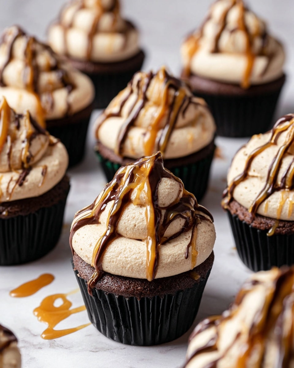 The image shows several chocolate cupcakes in black liners arranged closely together on a white marbled surface. Each cupcake has one thick, round layer of light brown, whipped frosting on top, shaped into a soft peak. Over the frosting, there are thin drizzles of dark chocolate and caramel sauces, creating a mixed pattern of dark brown and golden lines. The texture of the frosting looks smooth and creamy, contrasting with the dense, moist chocolate cupcake base. Some caramel sauce has lightly dripped onto the white marbled surface around the cupcakes. photo taken with an iphone --ar 4:5 --v 7