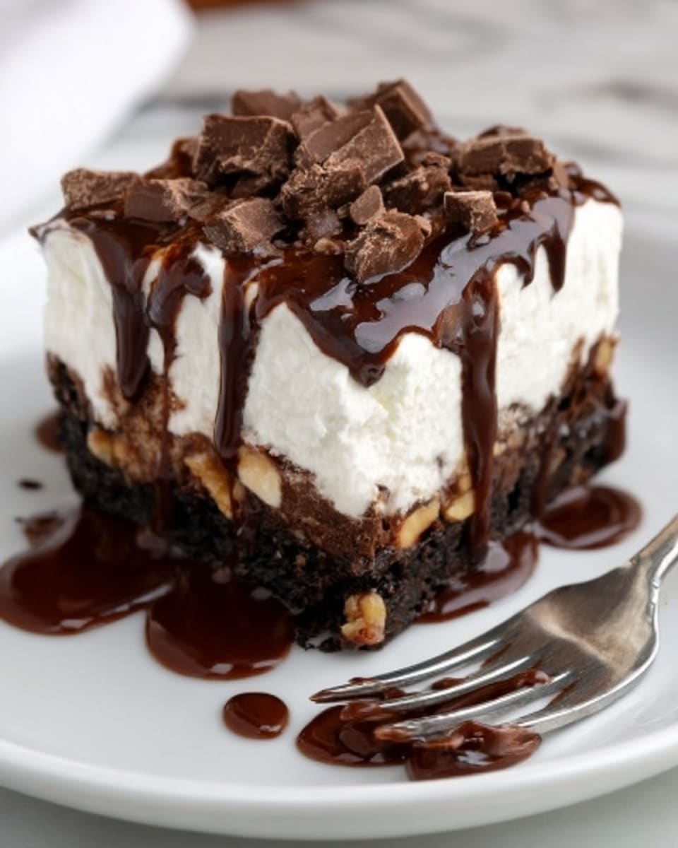 A thick square piece of chocolate dessert on a white plate with chocolate sauce spread underneath and some dripping off the sides. The dessert has three layers: a bottom layer of dark, dense chocolate with bits of nuts, a thick, smooth white cream layer in the middle, and a topping of chopped chocolate pieces scattered over the cream. Dark chocolate syrup is drizzled generously on top and slightly down the sides of the dessert. A silver fork lies next to the dessert with some chocolate sauce near it. The background is a white marbled surface. Photo taken with an iphone --ar 4:5 --v 7