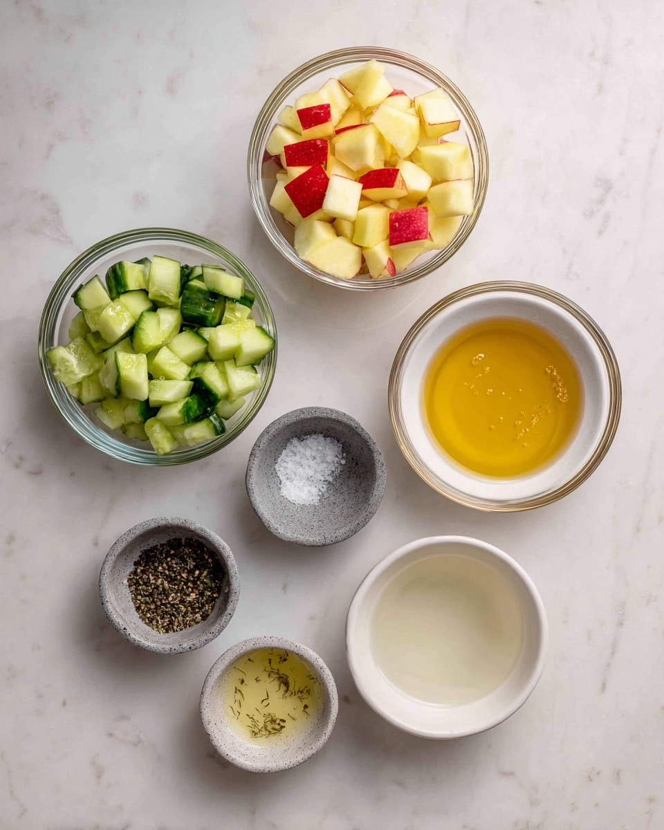 The image shows a white marbled surface holding six small bowls arranged in a loose circular pattern. At the top center, there is a clear glass bowl filled with small, light yellow and red apple cubes. Below and slightly left, another clear glass bowl contains bright green cucumber pieces with some darker green skin visible. To the right of the cucumber bowl is a white bowl with golden honey inside, showing a smooth and shiny texture. Below the honey bowl, slightly to the left, is a gray stone bowl holding a light clear liquid labeled vinegar. Below that and a little to the left is a white bowl with lemon juice, pale and milky in color. At the bottom left corner, a smaller gray stone bowl contains salt and black pepper, with its slightly grainy texture visible. All bowls sit neatly on the white marbled surface. Photo taken with an iphone --ar 4:5 --v 7