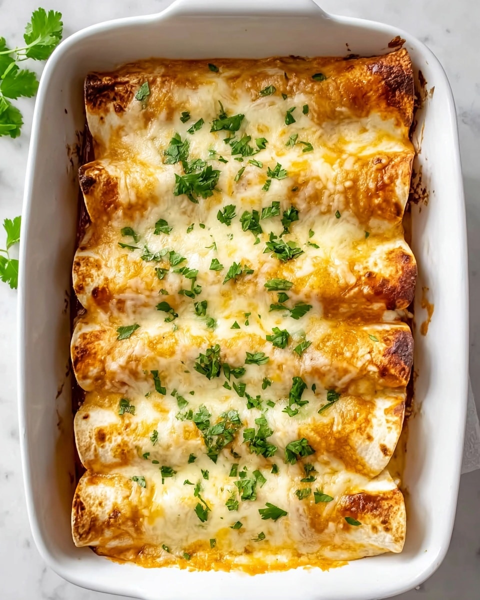 A white baking dish filled with five rolled enchiladas lined up closely side by side, each covered with a thick layer of melted, golden-yellow cheese with a slightly browned edge. Bright green chopped fresh parsley is scattered evenly across the top, adding fresh color. The edges of the enchiladas show some crispiness where the cheese has browned. The dish rests on a white marbled surface with small green parsley leaves placed casually nearby for decoration. Photo taken with an iphone --ar 4:5 --v 7