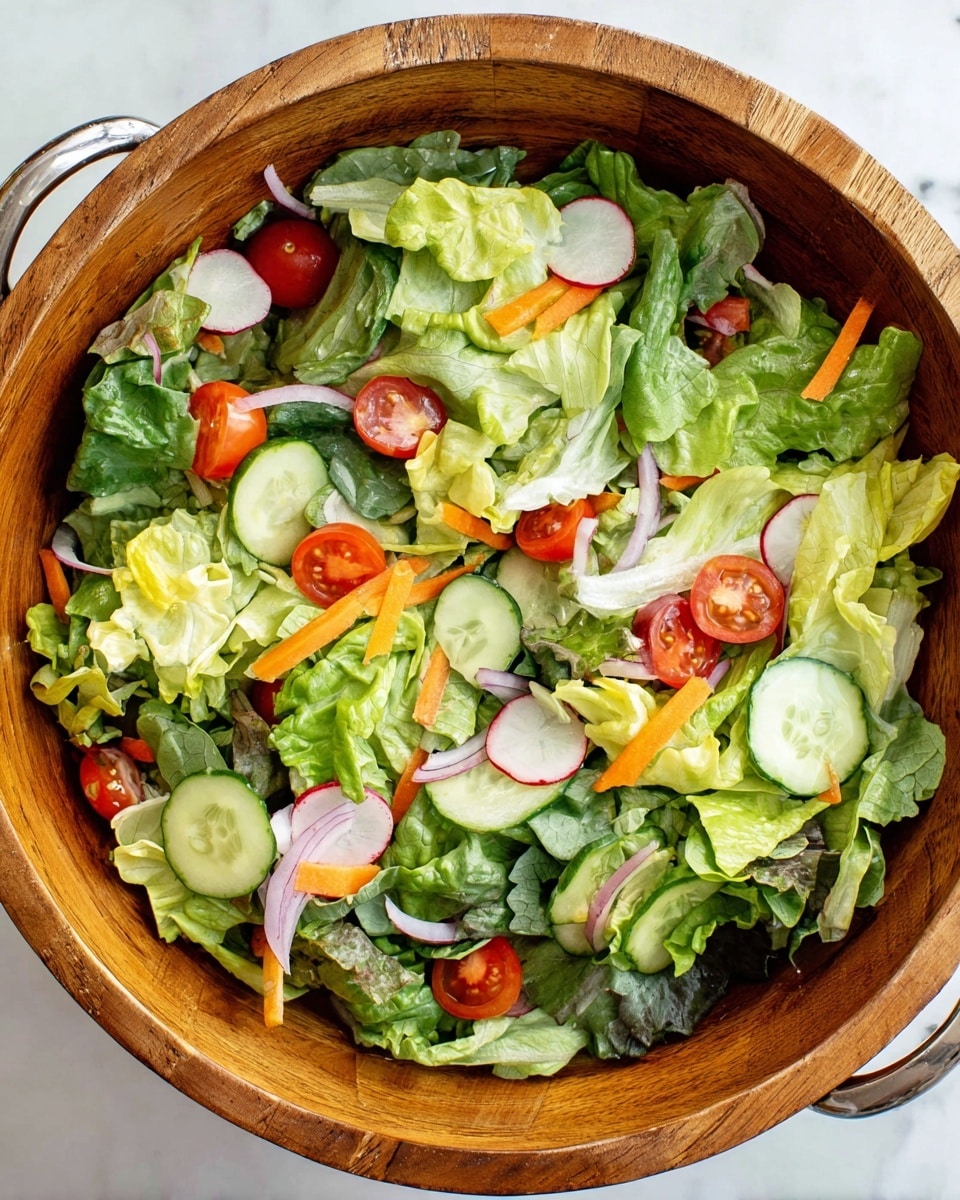 A close-up top view of a wooden bowl filled with a fresh salad on a white marbled surface. The salad has three main layers visible: the base layer consists of torn leafy greens in light and dark green shades, including romaine and spinach leaves. On top, there are thin slices of round cucumber with pale green centers and dark green edges, scattered red cherry tomato halves, and thin round slices of radish with white centers and red edges. Thin, short orange strips of carrot and a few rings of purple-red onion are spread evenly throughout the salad, adding more color and texture. The wooden bowl has a natural grain texture and silver handles on each side. photo taken with an iphone --ar 4:5 --v 7