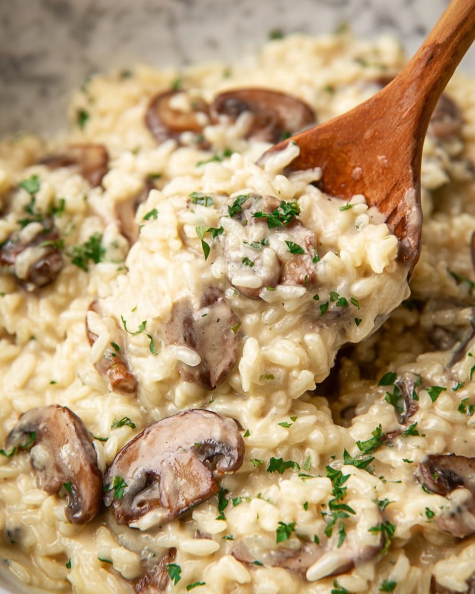 The image shows a close-up of creamy risotto mixed with sliced mushrooms, with the risotto being pale yellow and smooth in texture. The mushrooms are brown with a slightly glossy surface, scattered evenly throughout the risotto. Bits of fresh green herbs are sprinkled on top, adding contrast and a touch of brightness. A wooden spoon is lifting a portion of the risotto, showing the thick texture and layers of rice and mushrooms blended together. The dish is presented on a white marbled surface. photo taken with an iphone --ar 4:5 --v 7