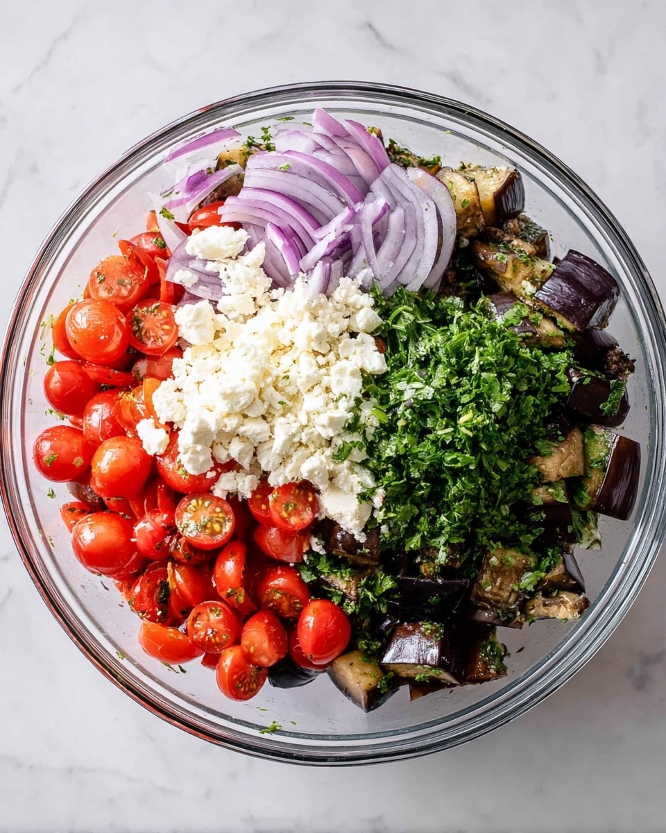 A clear glass bowl sits on a white marbled surface filled with several layers of ingredients. The bottom layer contains dark brown roasted eggplant pieces mixed with thin slices of purple onions. On top of that, there are bright red halved cherry tomatoes covering one side of the bowl. A white crumbly layer of cheese sits near the center, and fresh chopped green herbs occupy the other side of the bowl, creating a colorful, textured mix. Photo taken with an iphone --ar 4:5 --v 7
