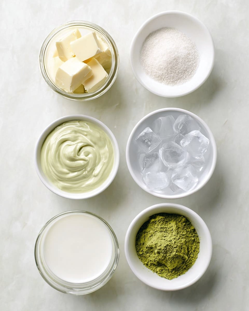 The image shows six small white bowls on a white marbled surface, each containing different ingredients. Starting from the top left, there is a glass jar filled with pale yellow squares of butter. To its right, a white bowl holds a pile of white granulated sugar with a small mound in the center. Below the jar, a white bowl contains a smooth, pale green creamy mixture with a swirl pattern on top. To the right of that, another white bowl is filled with bright green powder, slightly heaped. On the bottom left, a clear glass bowl holds white liquid, opaque and smooth. To its right, a white bowl is full of clear ice cubes, some stacked on each other, showing sharp edges and light reflections. The setup is neat and clean, with soft natural light that emphasizes the color and texture of each ingredient, photo taken with an iphone --ar 4:5 --v 7